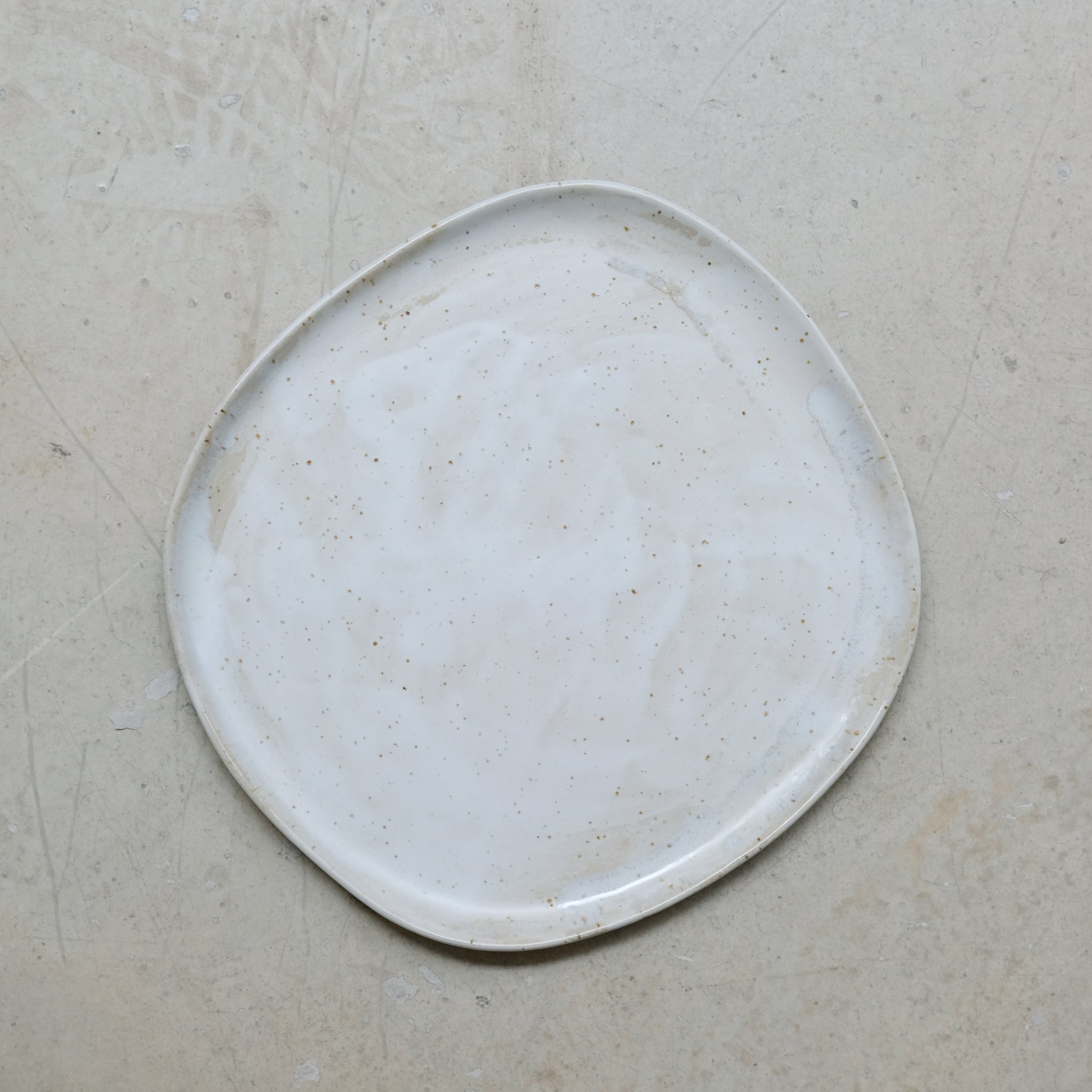 Assiette en grès pyrité D 27cm - blanc moucheté de Sonia Deleani chez Brutal Ceramics