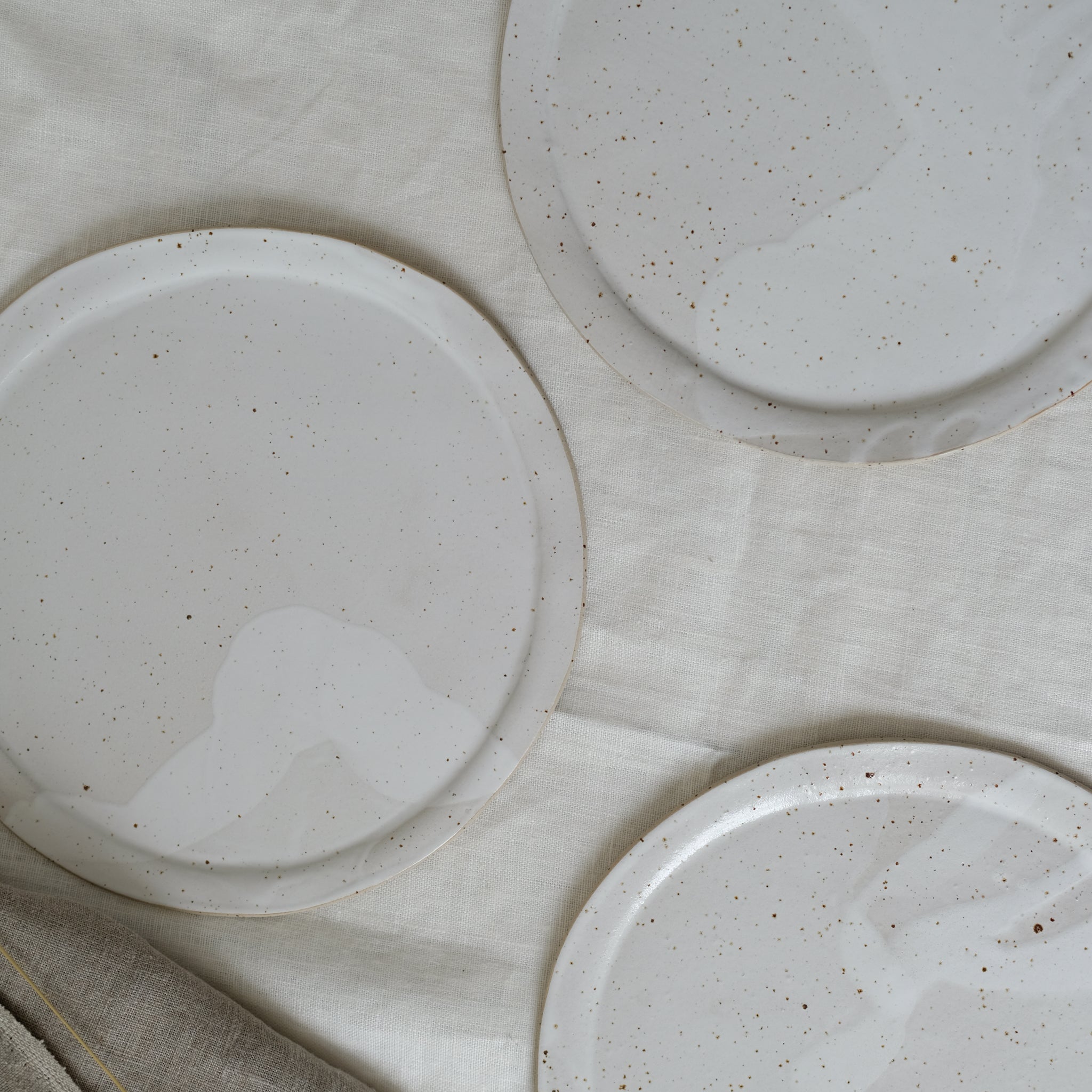 Grande assiette en grès blanc moucheté par Lucie Faucon chez Brutal Ceramics