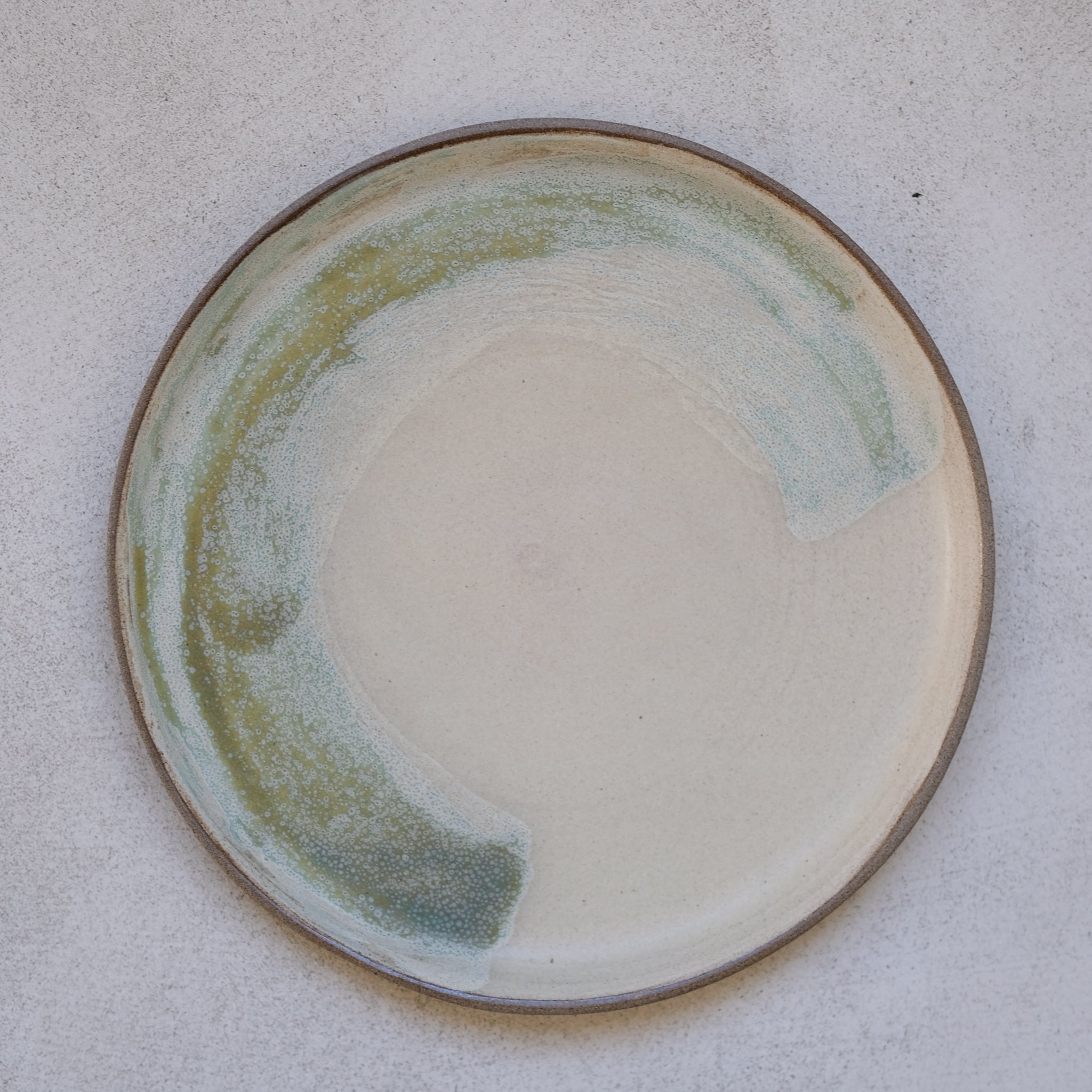 Assiette en grès gris D24cm - vert pistache d'Eva Kengen chez Brutal Ceramics