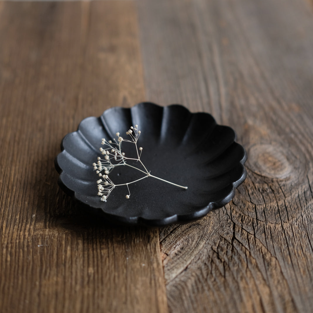 Assiette en grès noire en forme de fleur réalisée par le céramiste Shin Ito