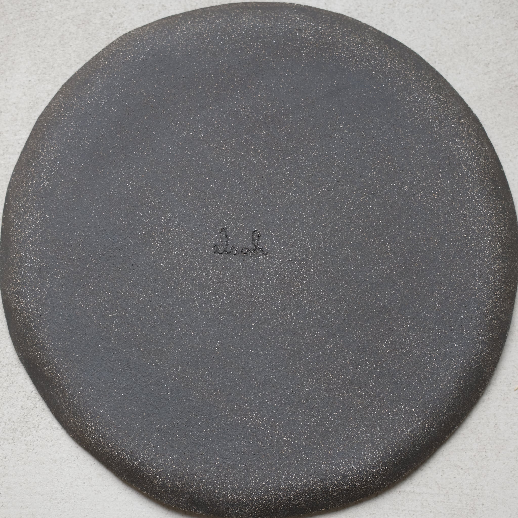 Assiette en grès noir chamotté de la céramiste Elsa Haas