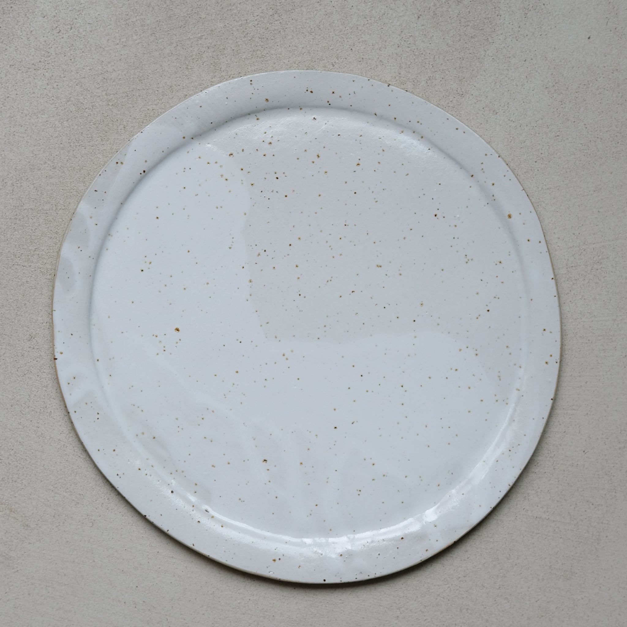 Grande assiette en grès blanc moucheté par Lucie Faucon chez Brutal Ceramics