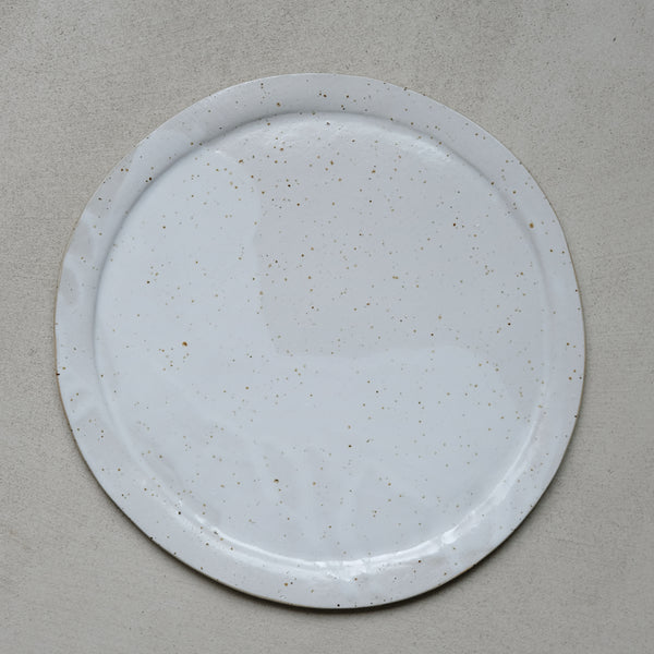Grande assiette en grès blanc moucheté par Lucie Faucon chez Brutal Ceramics
