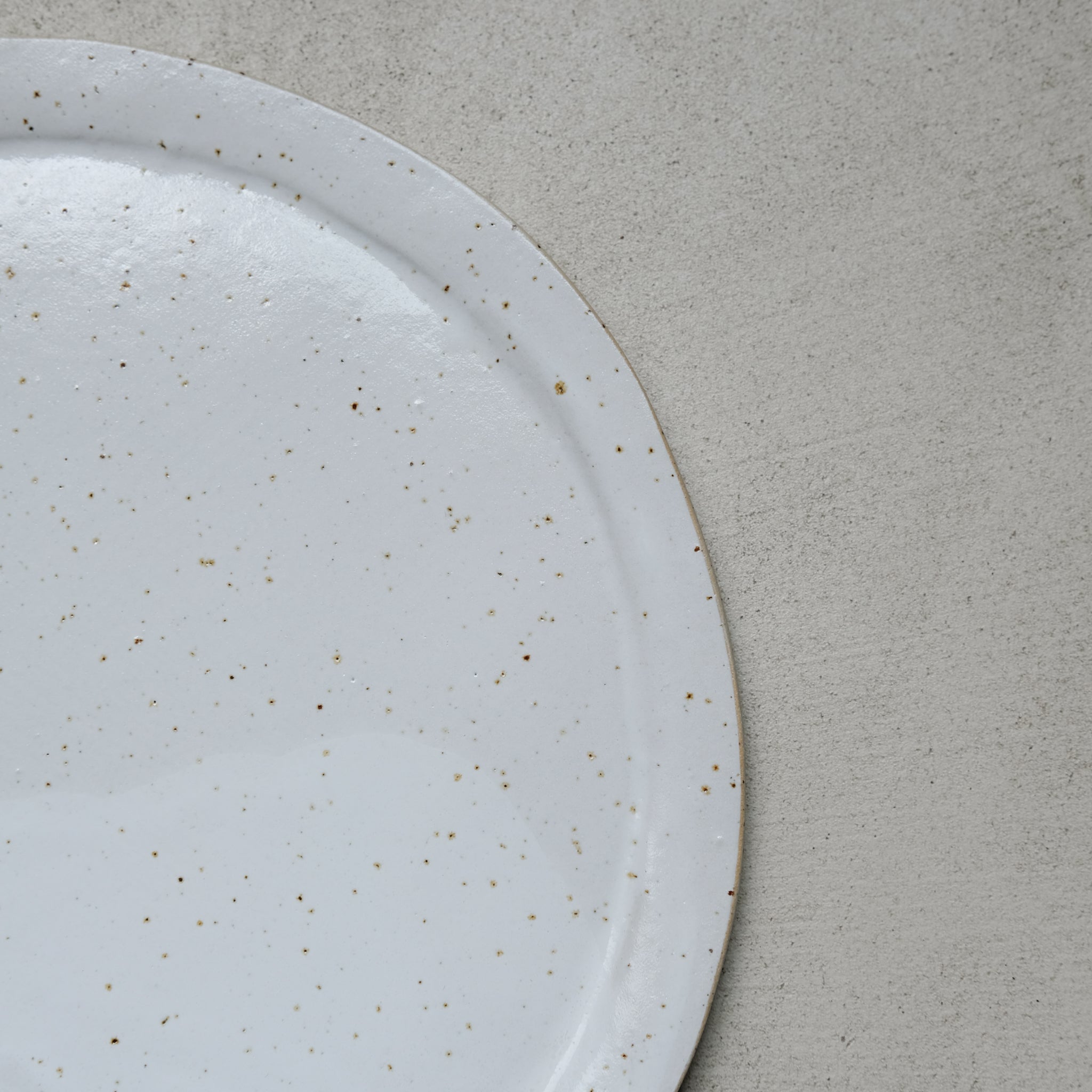 Grande assiette en grès blanc moucheté par Lucie Faucon chez Brutal Ceramics