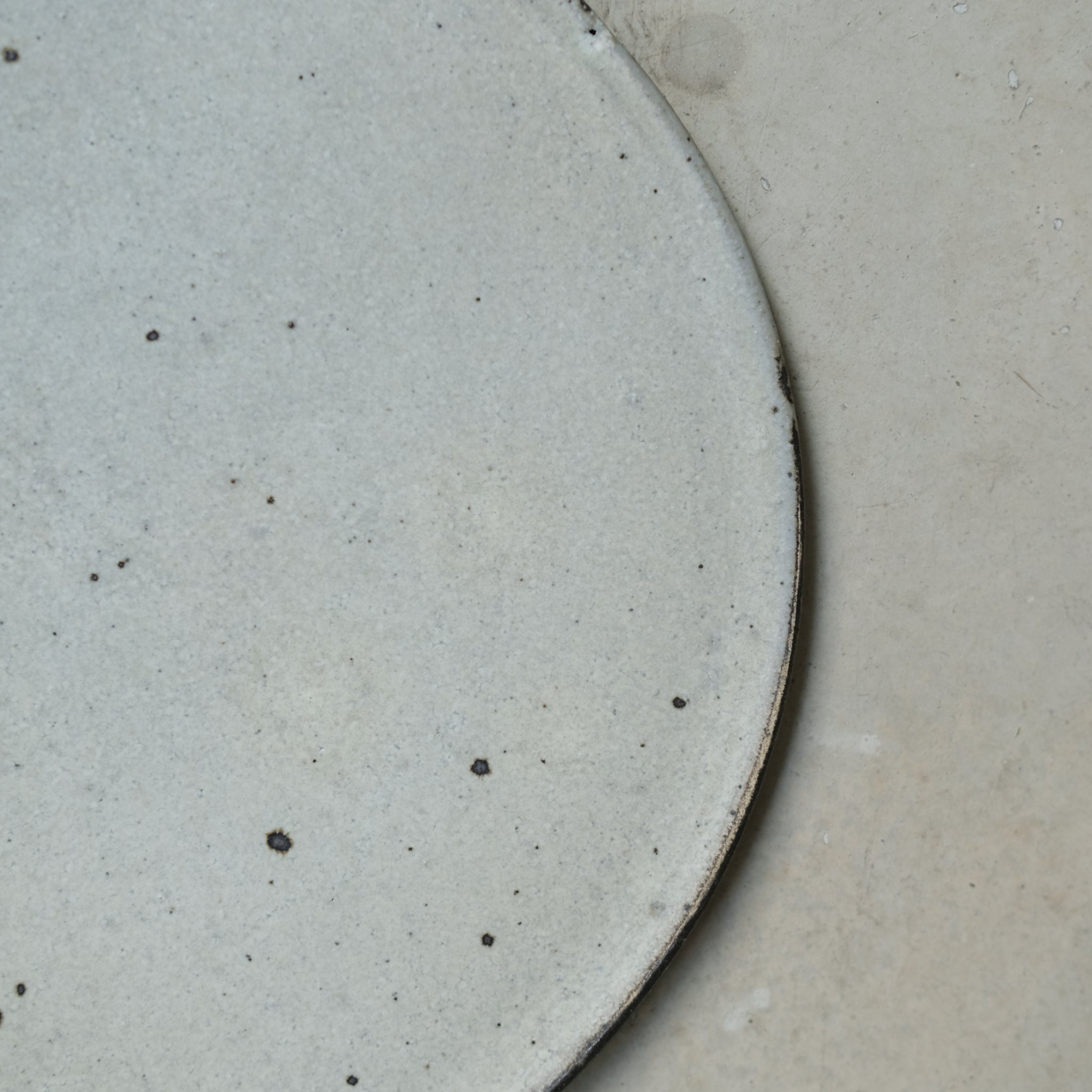Assiette en grès gris D 26cm - blanc cassé de Ryutaro Yamada chez Brutal Ceramics