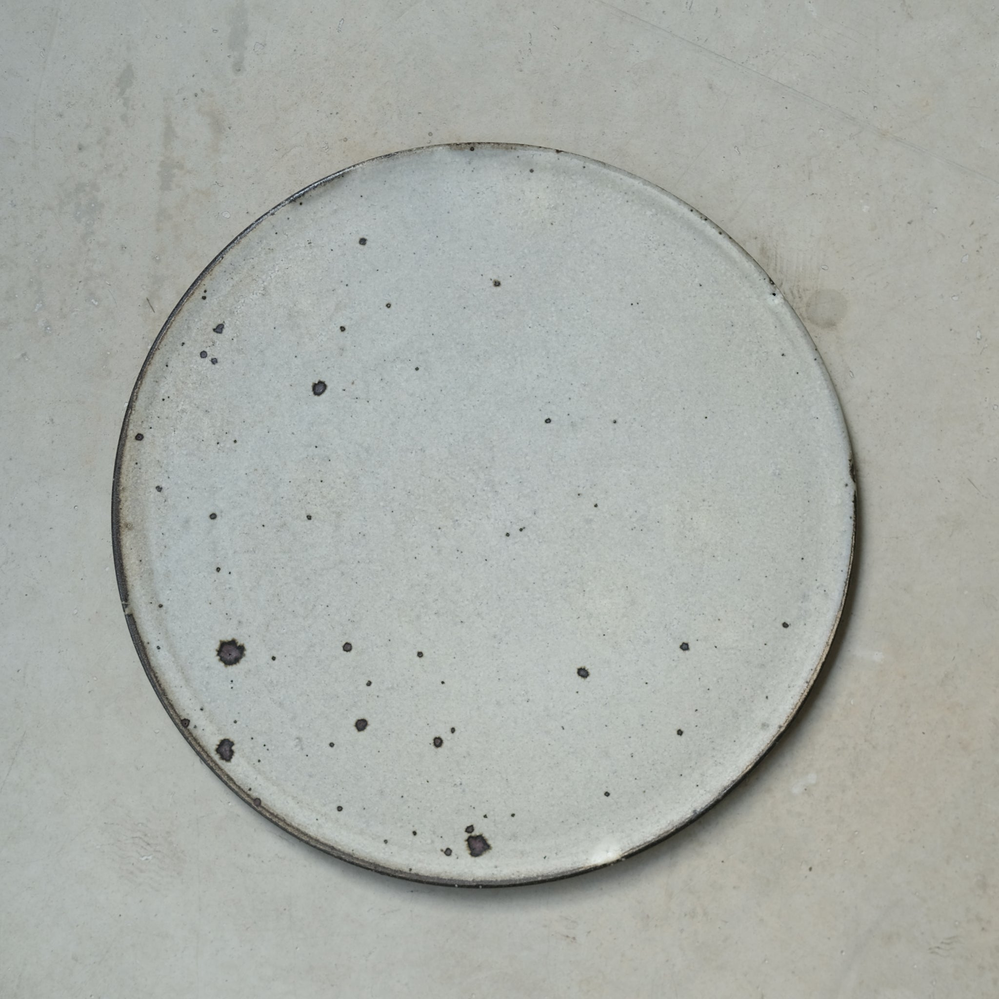 Assiette en grès gris D 26cm - blanc cassé de Ryutaro Yamada chez Brutal Ceramics