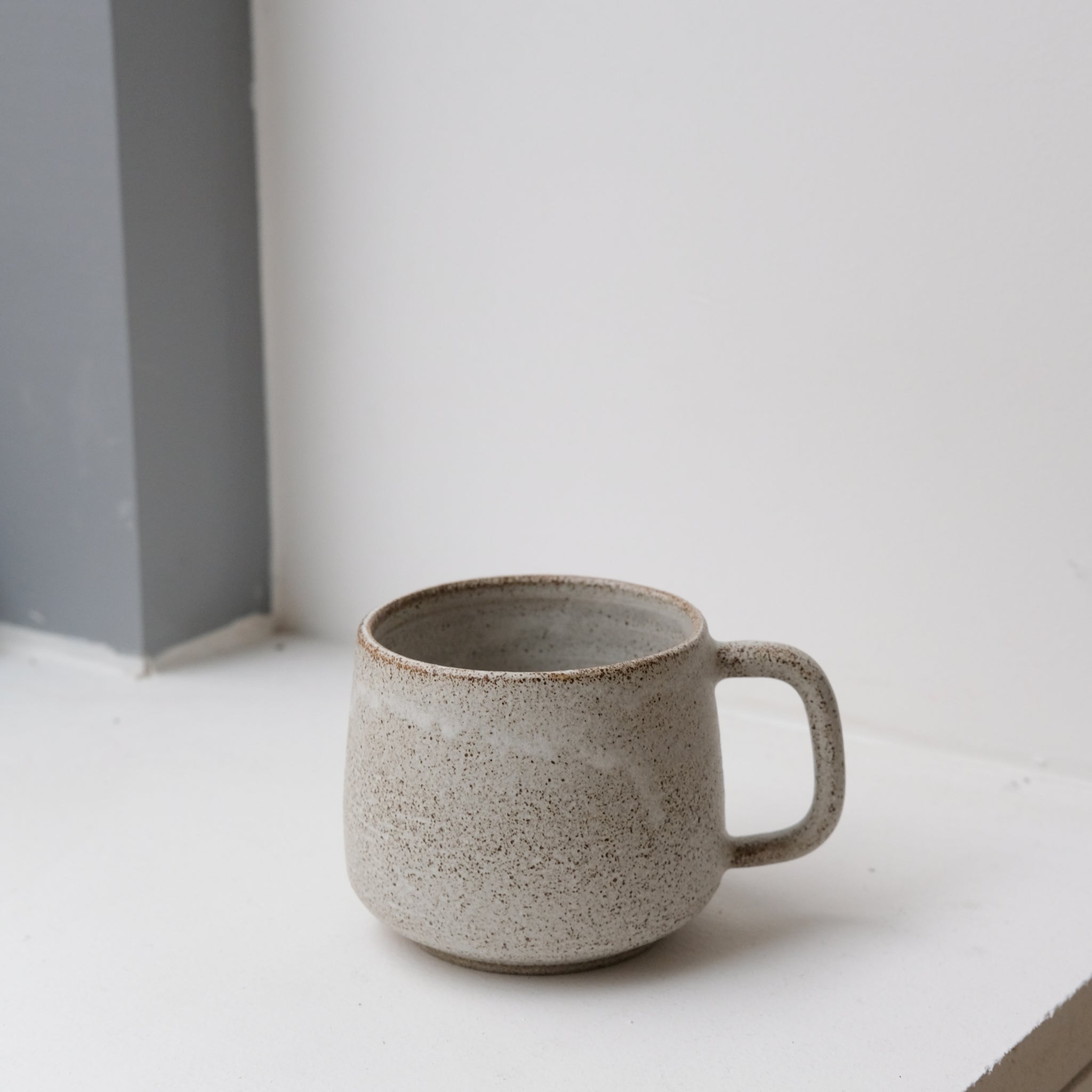 Mug en grès blanc et brun moucheté de Laurence Labbé chez Brutal Ceramics