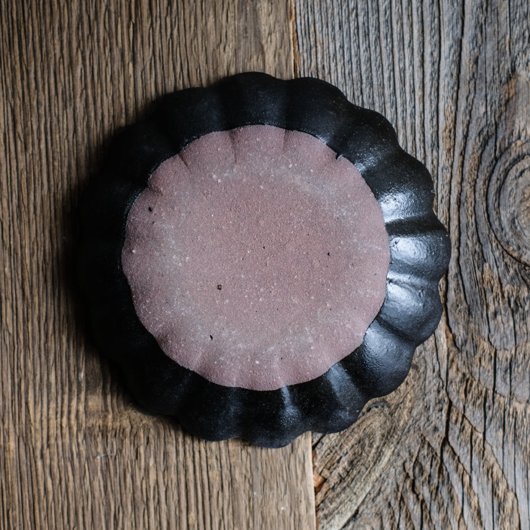 Assiette en grès noire en forme de fleur réalisée par le céramiste Shin Ito
