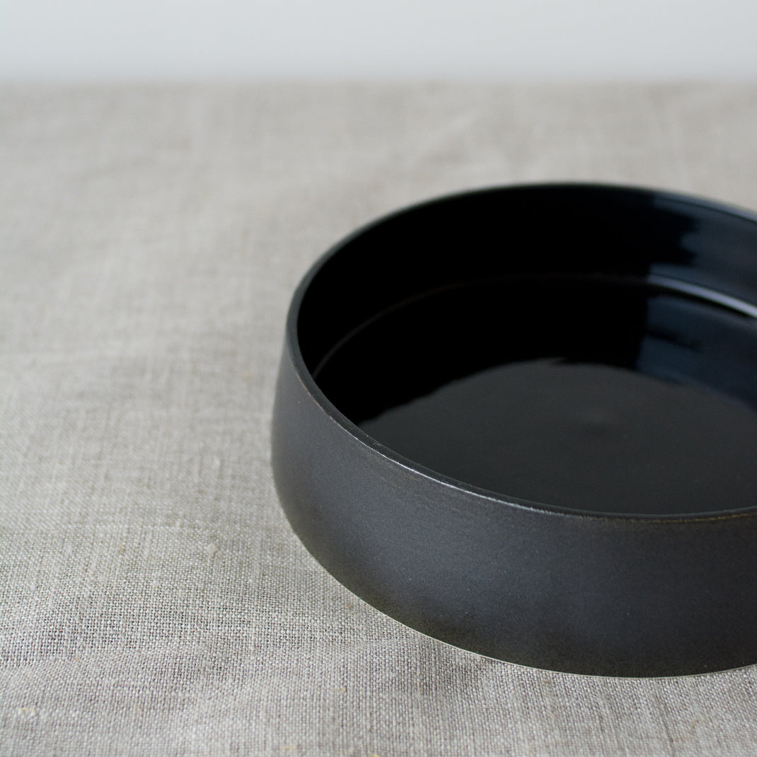 Assiette creuse noire faite à la main dans l'atelier parisien de Pia Van Peteghem, céramiste