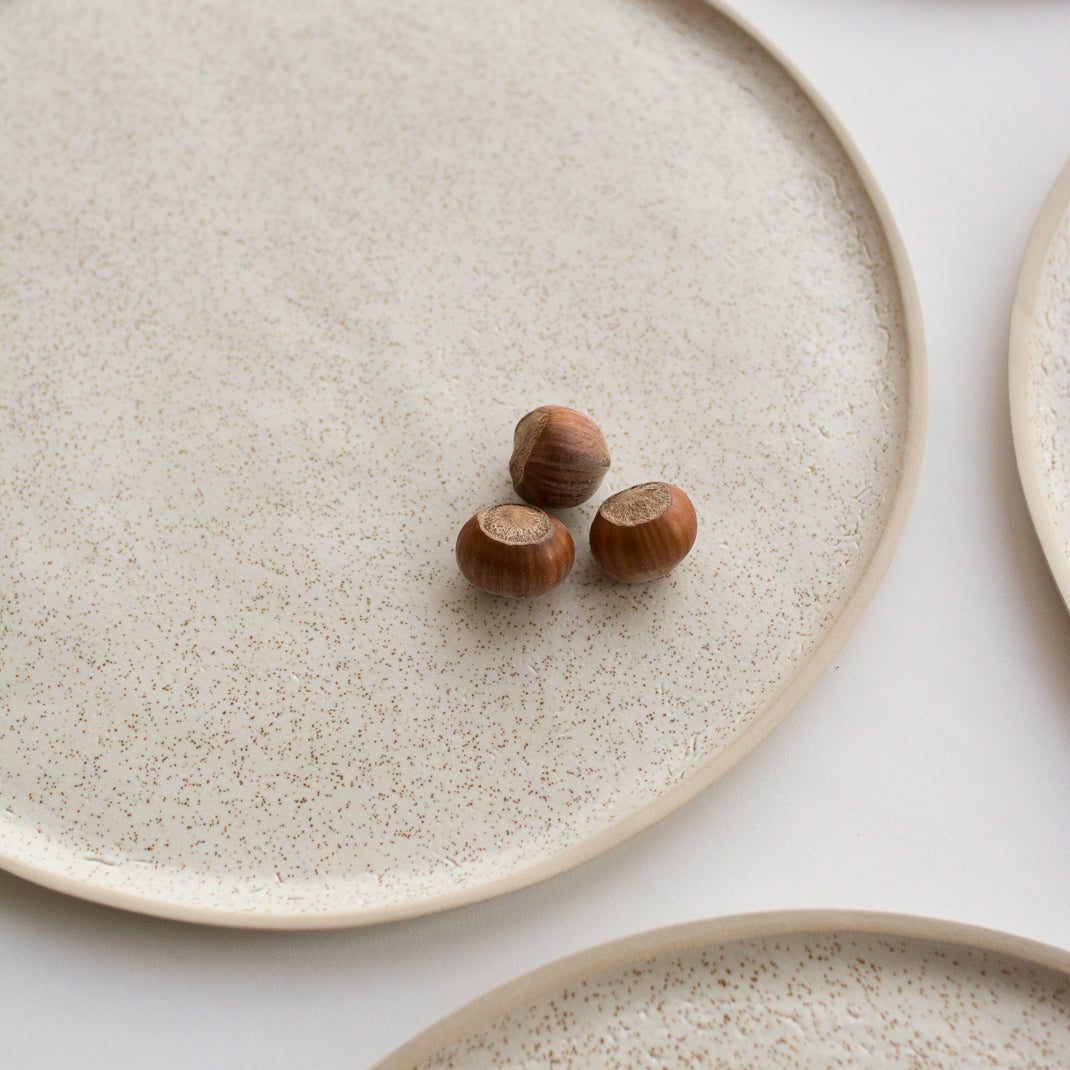 Assiette en grès émaillé blanc moucheté de Laurette Broll, céramiste