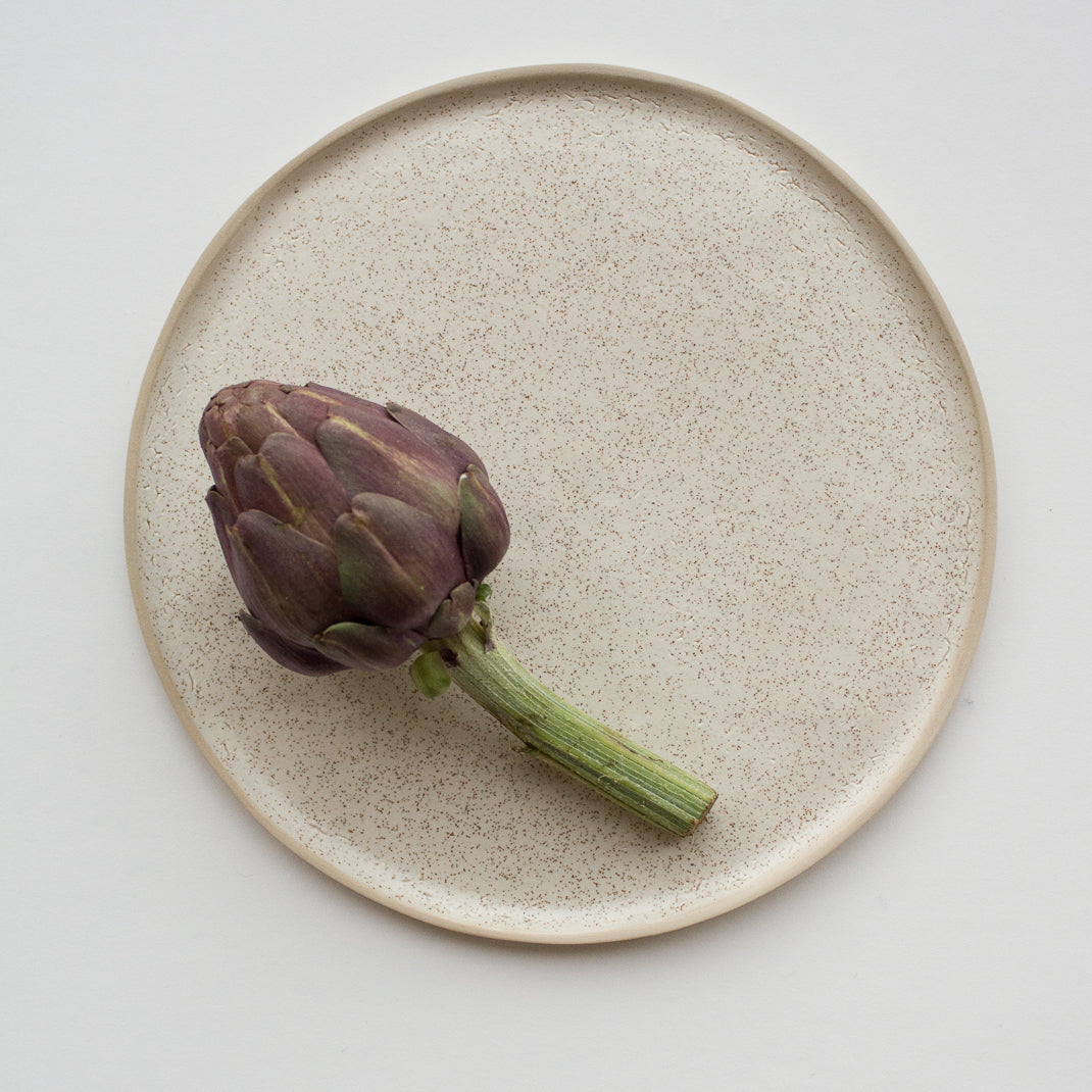 Assiette en grès émaillé blanc moucheté de Laurette Broll, céramiste