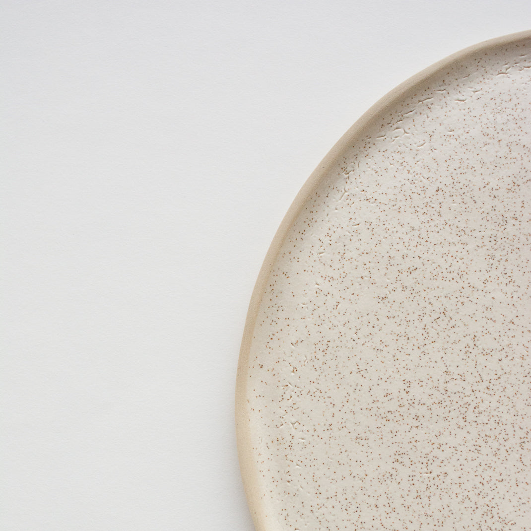 Assiette en grès émaillé blanc moucheté de Laurette Broll, céramiste