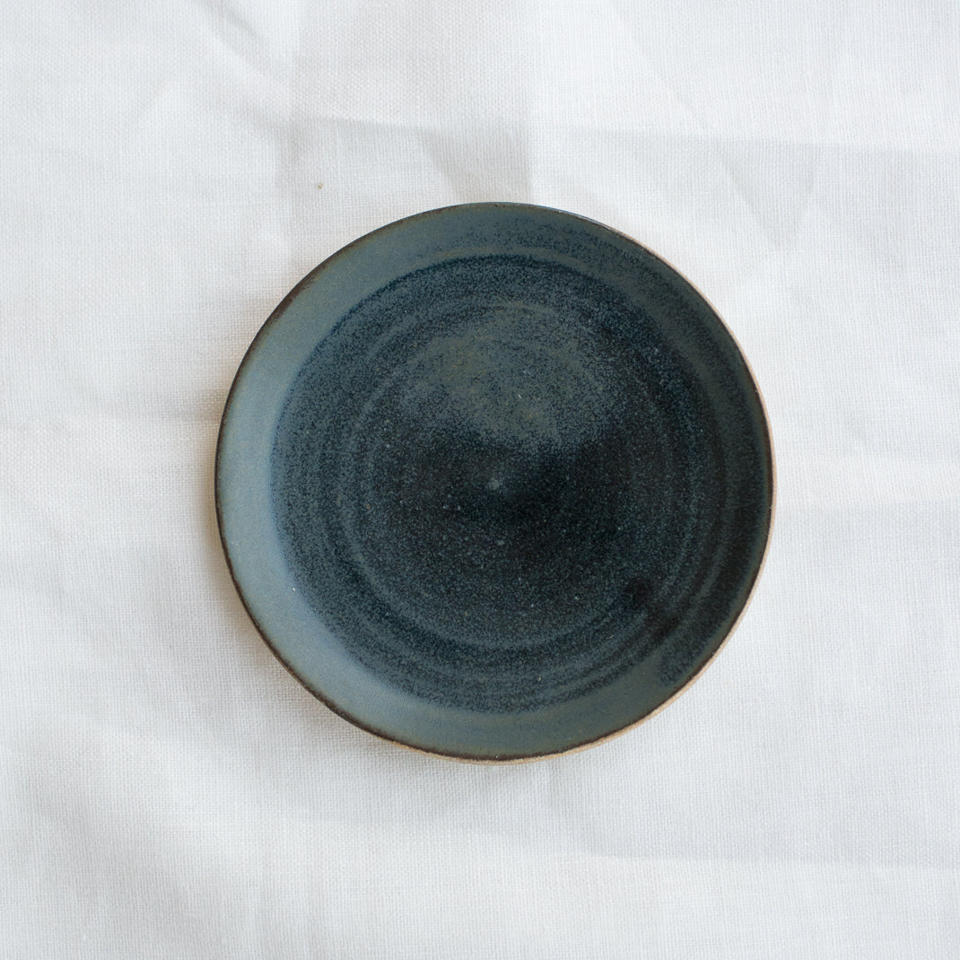 Petite assiette verte foncée realisée à la main par la céramiste Patricia Vieljeux, dans son atelier parisien